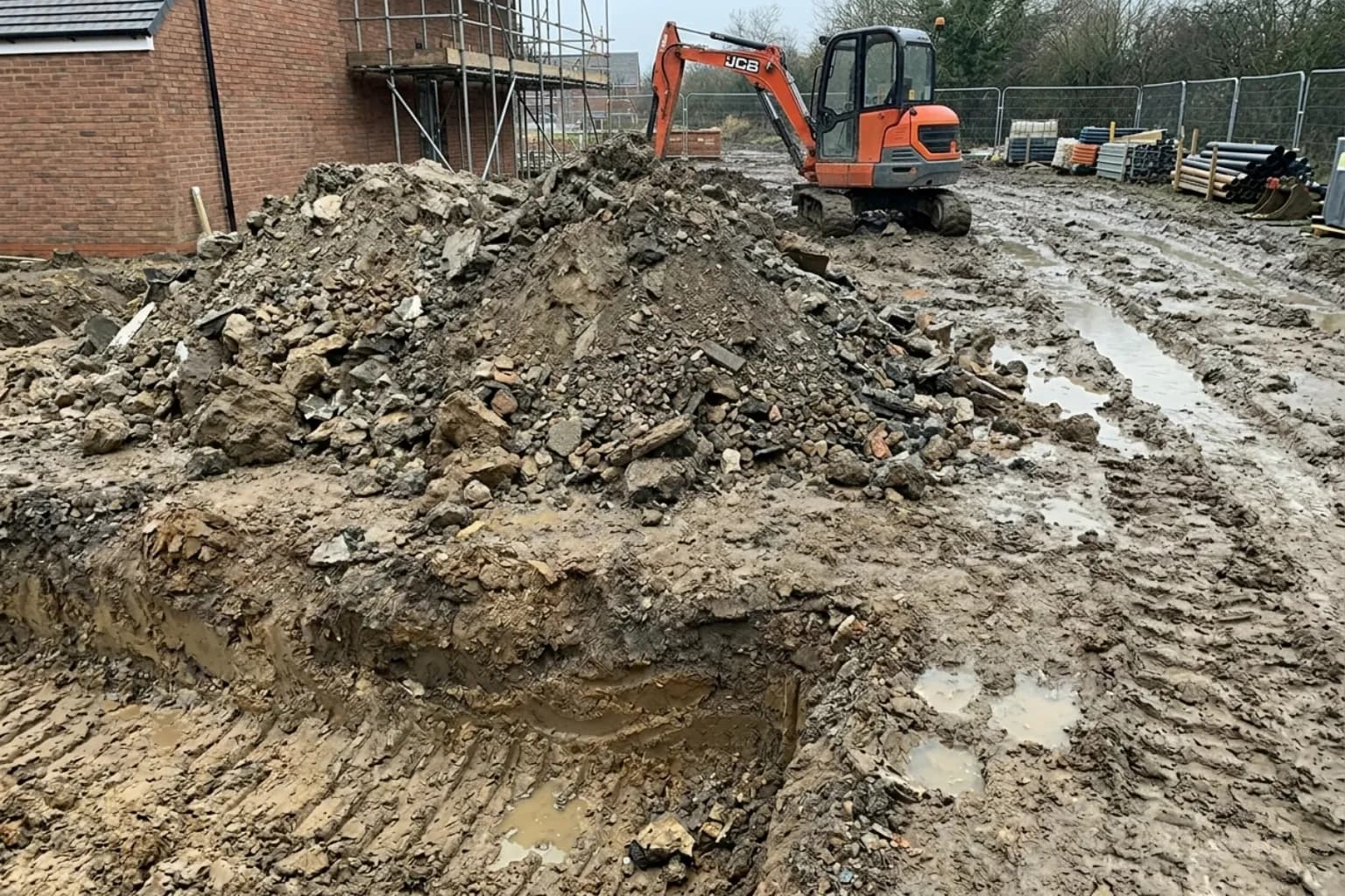 Foundation trench and grab-hire scale spoil heap at a groundworks site, hired through Skyward Skip Hire